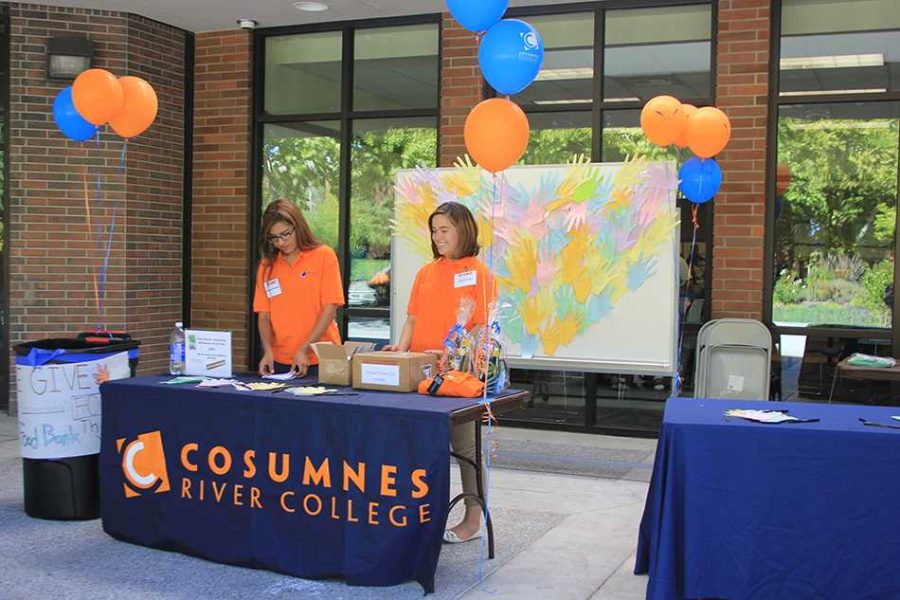 Monique Maldonado (left) and Anna Lozano (right), both CRC students, attract student attention to their table by passing out paper hands and offering scratcher cards for discounts in the bookstore.