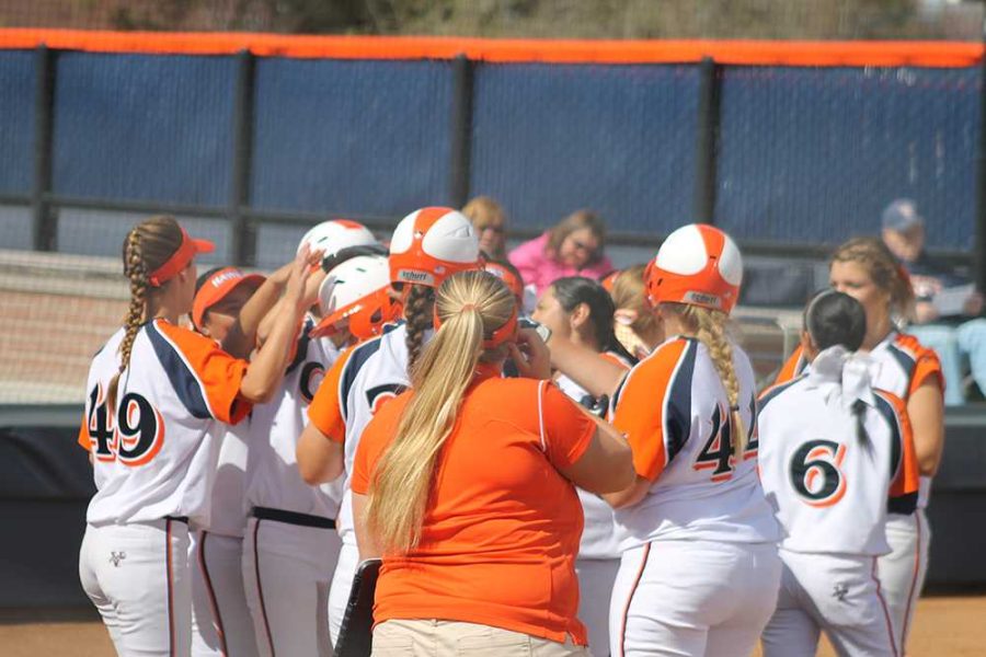 Hawks players celebrate at home plate and pat the helmet of sophomore utility Hanna Miller after Miller's first inning home run brought them an early lead in game one against Butte College. 