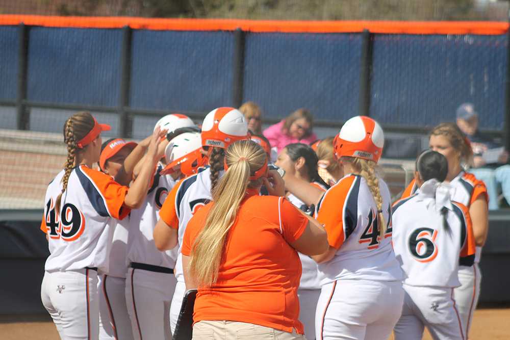 Hawks players celebrate at home plate and pat the helmet of sophomore utility Hanna Miller after Miller's first inning home run brought them an early lead in game one against Butte College.