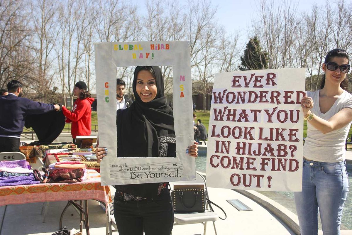 Jamie Meastas, 22, an undeclared major (left) and 20-year-old cinematography major Yalda Biglari (right) took part in the Muslim Student Association event which included interactive props like the picture frame held by Jamie that allowed students to take a picture of themselves trying on a hijab on Feb. 25. 