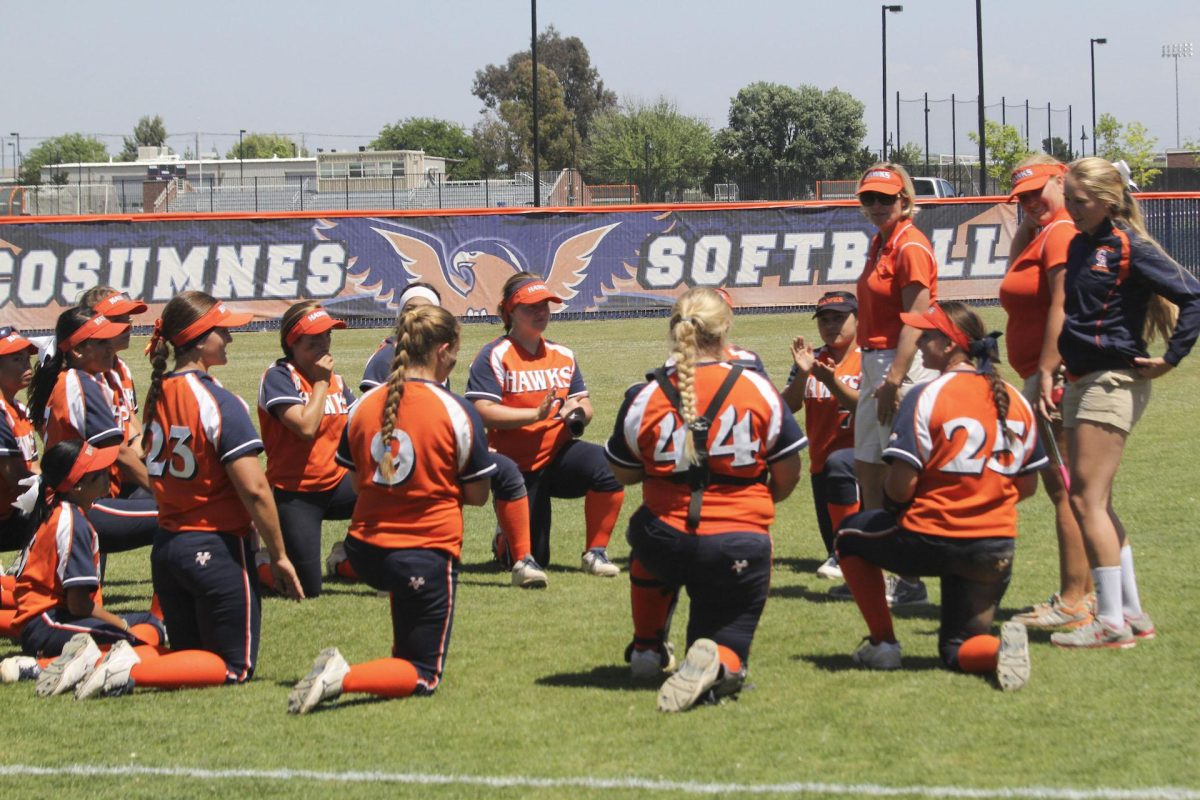 The Hawks softball team talking with head coach Kristy Schroeder after their 6-1 win against Fresno City.