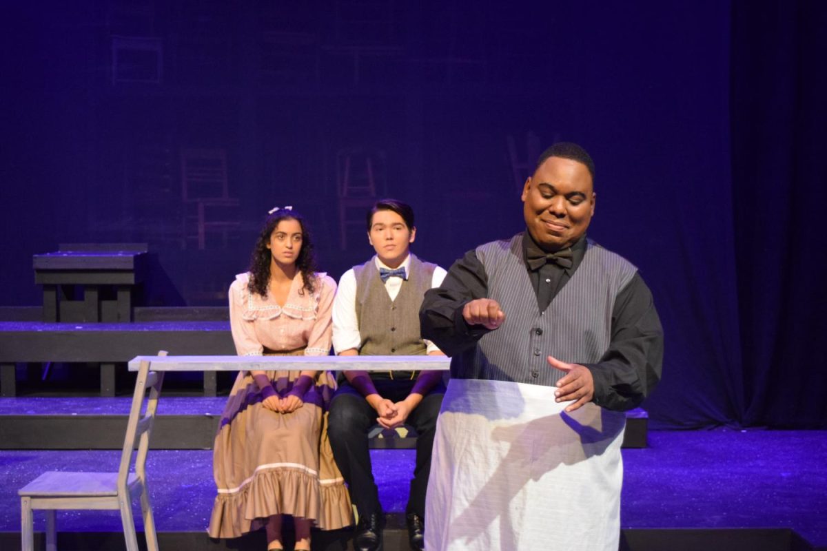 Store Manager (Coleman Daniel) scoops ice cream for young lovers, Emily (Sara Alnassiri) and George (David Johnson) in a performance of Our Town on Oct. 13.