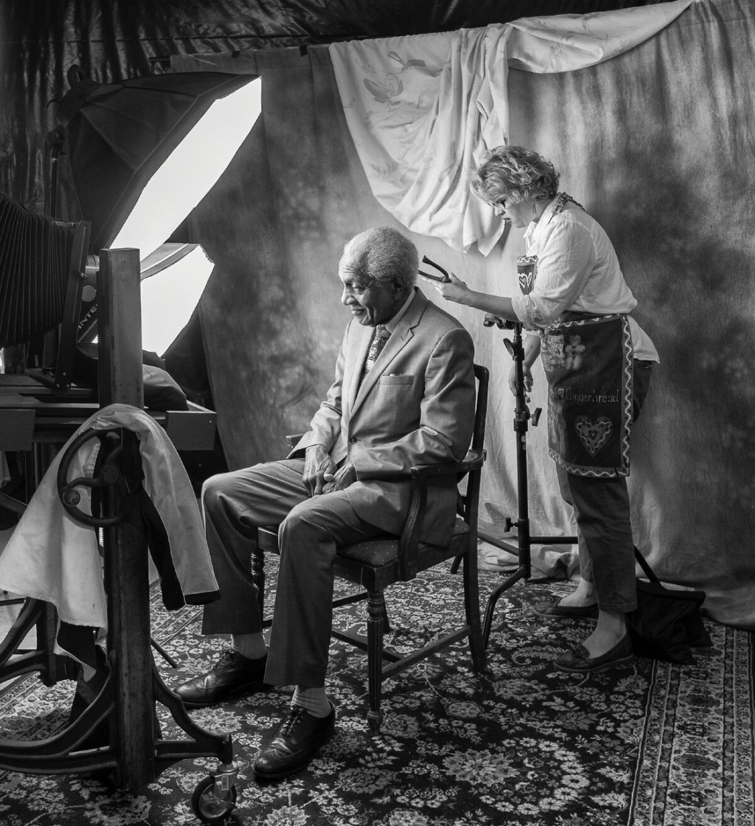 In a photo taken by her husband, who served as an assistant during the project, Professor Kathryn Mayo preps one of her subjects, F.D. Reese, before taking his photo as part of her sabbatical portrait project We Are Selma.