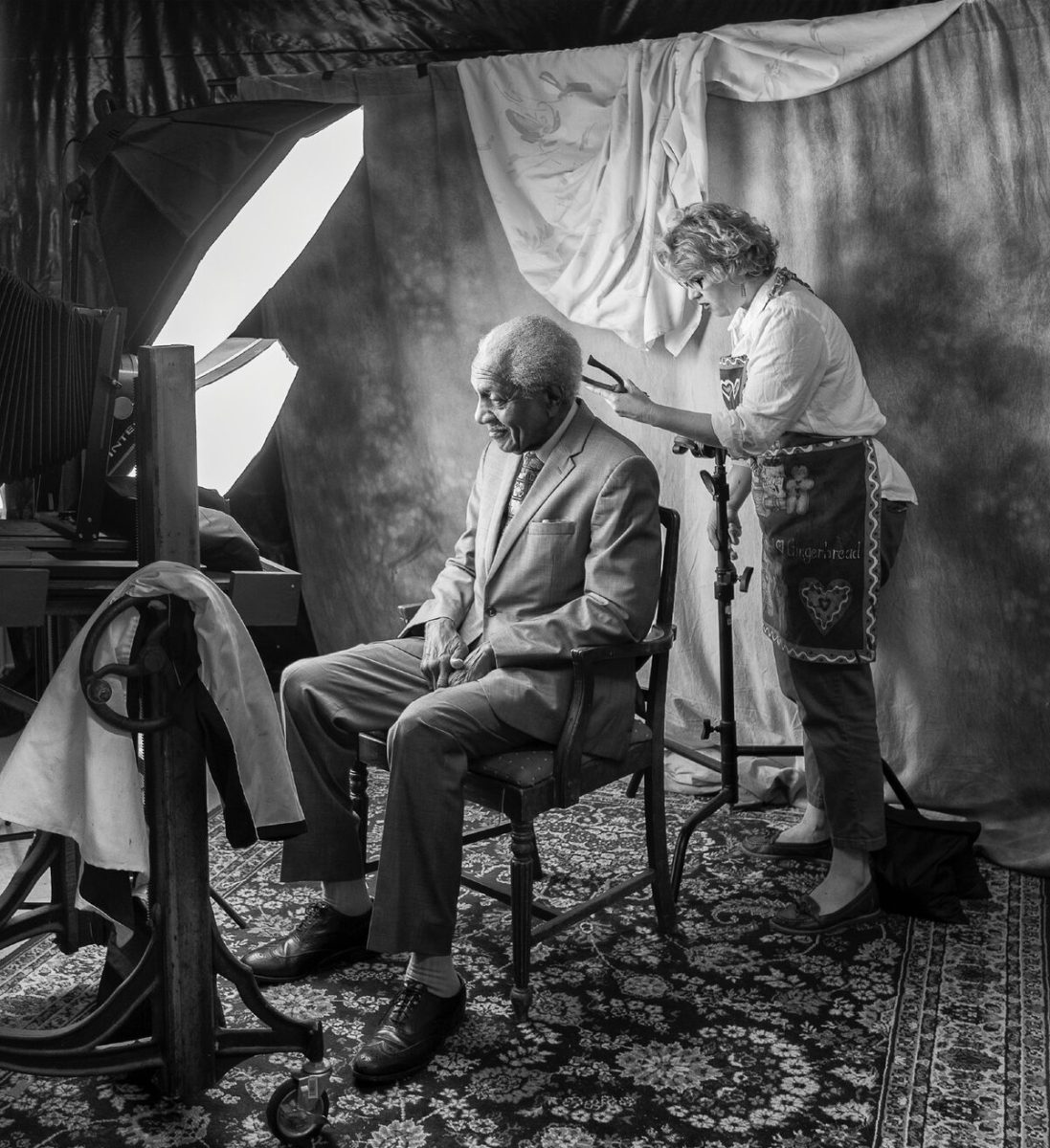 In a photo taken by her husband, who served as an assistant during the project, Professor Kathryn Mayo preps one of her subjects, F.D. Reese, before taking his photo as part of her sabbatical portrait project "We Are Selma."