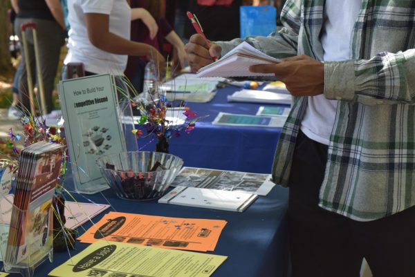 Person standing in front of a booth writes in a notebook.