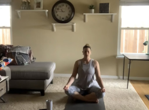 Yoga Professor and Women's Basketball Coach Coral Sage in her living room performing a yoga pose. Sage's yoga videos are used for her online classes and are accessible to her students and everyone on YouTube.