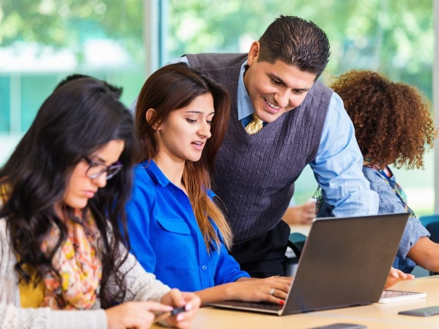 A professor and a student looking at a laptop. Student and professor relationships can be linked to student success and happiness.