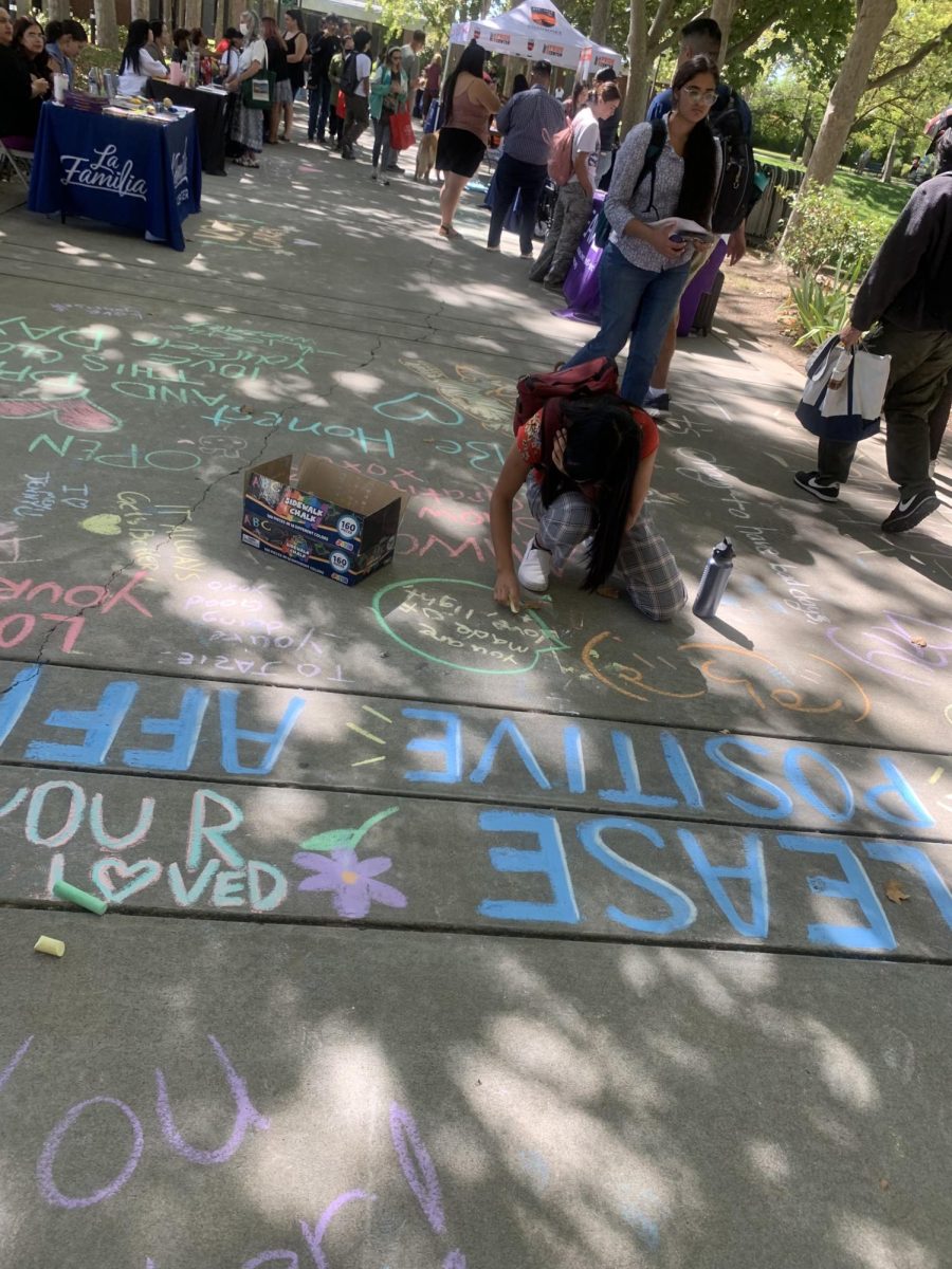 A+student+writes+an+affirmation+on+the+chalk+walk+at+Tuesdays+mental+health+fair.+The+fair+was+followed+by+a+lecture+from+Sacramento-based+Licensed+Marriage+and+Family+Therapist+Adriana+Rodriguez+on+Wednesday.