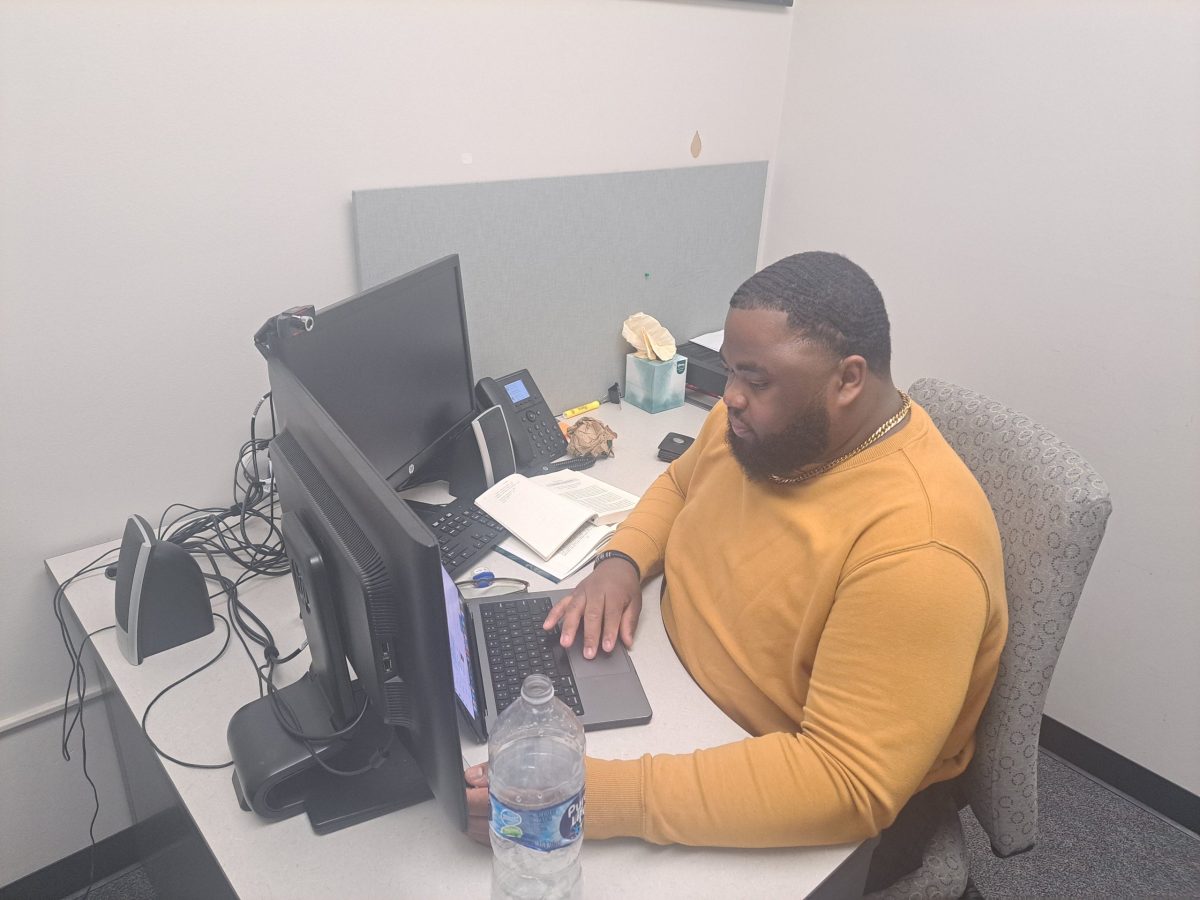 Malik Amos, Student Personnel Assistant for the Umoja Diop Scholar Program, works at his desk in the Umoja Center. The center is located at L-215 on the first floor of the library and provides community to African American and other students.