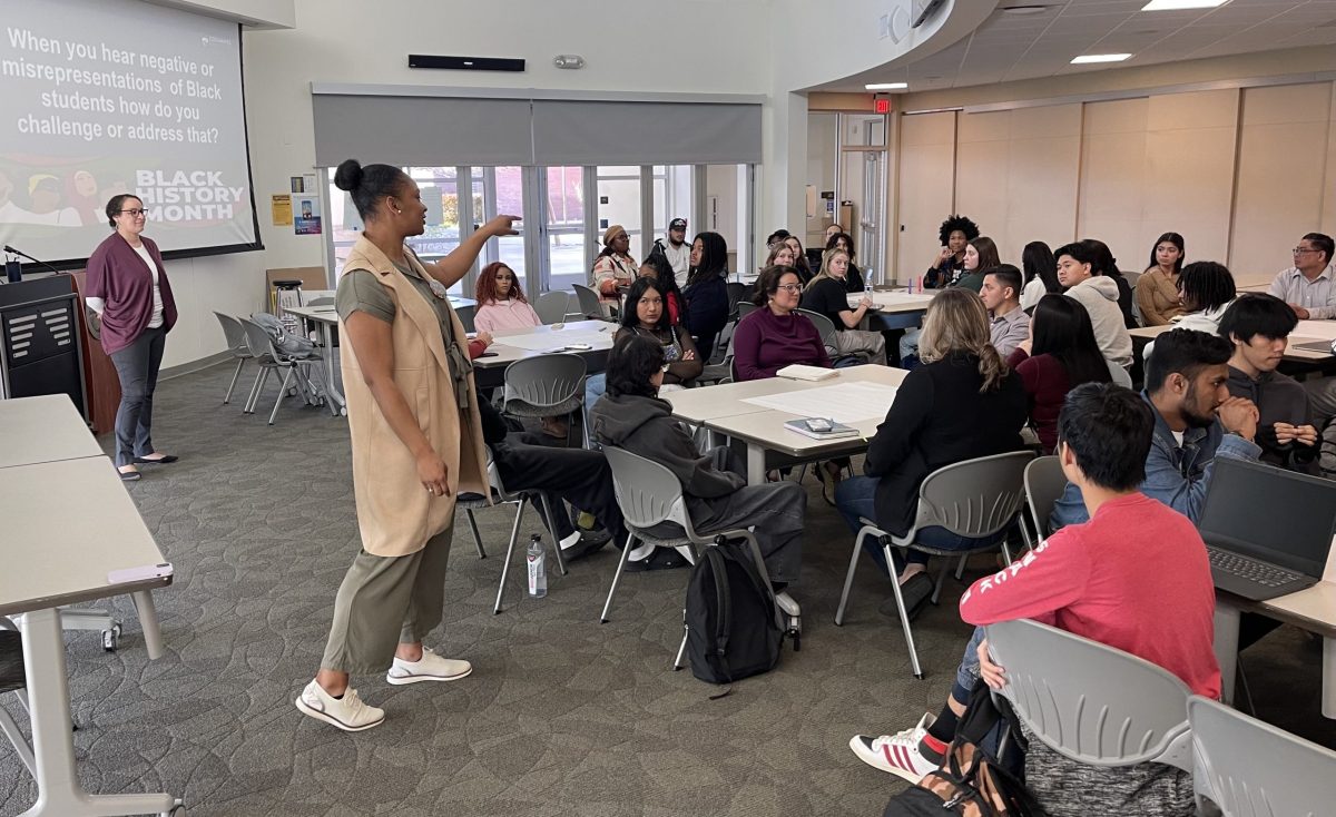  Director of Upward Bound and Interim Director of TRIO Student Support Services Trinity Wilson (left) asking different table groups questions about the black experience on campus. Wilson said she uses these events to emphasize the resources on campus for students.