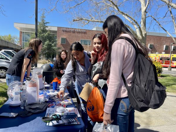 Students gather around the Student Support Services table in the quad for the Hawk CARES Care Fest event on March 19. A food truck, gifts and resources were provided to students to promote different services on campus and in the community.