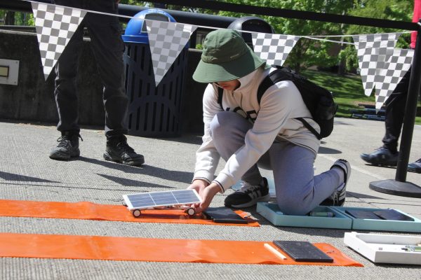 A middle school student stops a solar car at the end of the track. SMUD hosts the solar car race every year at Cosumnes River College for middle and high school students.