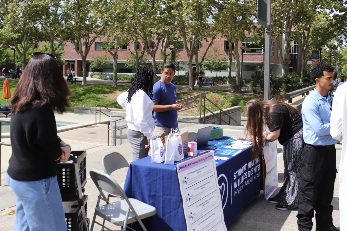 Mental health and wellness center employees speak with students at the Suicide Prevention Day table in front of the fountain in the quad on Sept. 10. The hope station was a board near the table for students to leave encouraging statements for other students. 