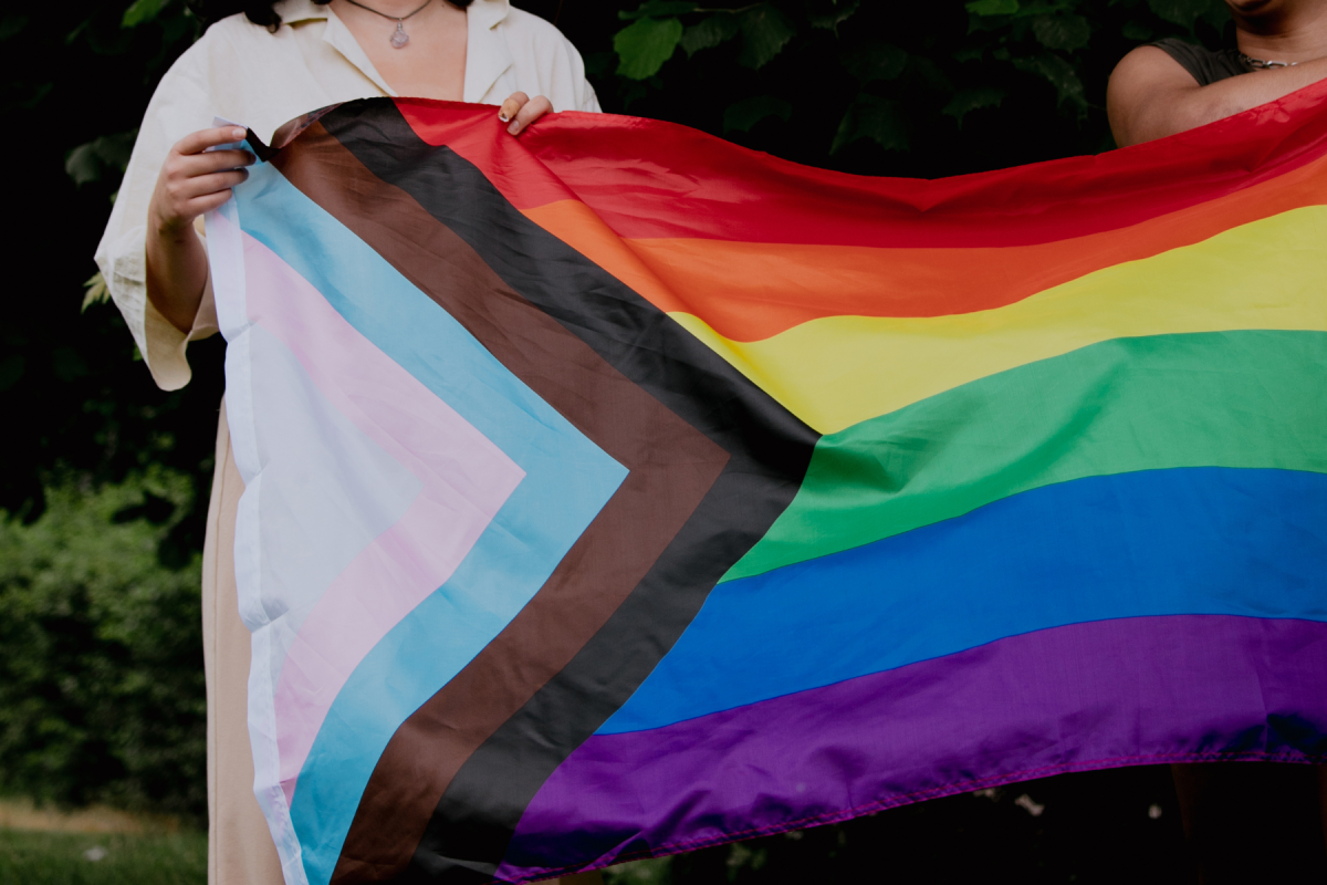 Individuals holding the progress pride flag, which symbolizes an inclusive approach to LGBTQ+ history. California has joined a multistate lawsuit in response to an executive order from the White House, challenging cuts to gender-affirming care.