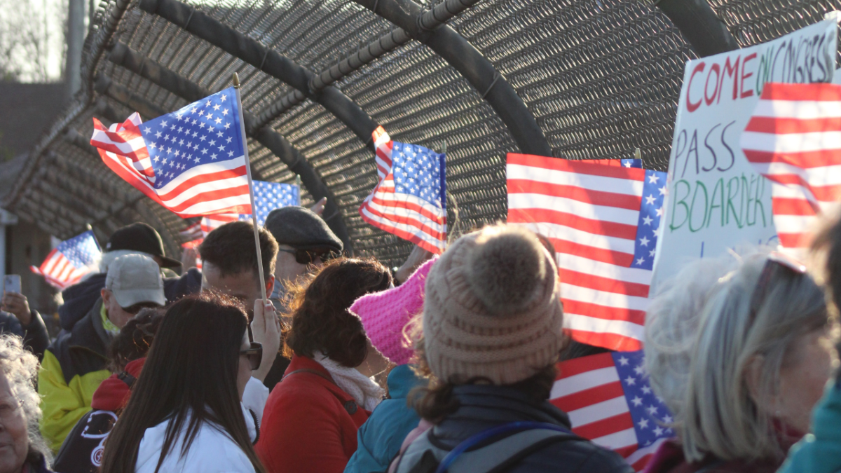 Protestors hold American flags and handmade signs at a vigil for Alex Pretti on 48th Street on Wednesday. The vigil was organized by local nurses and community members in remembrance of Pretti, a Minneapolis intensive care nurse, who was killed last month during an altercation with ICE officers. 